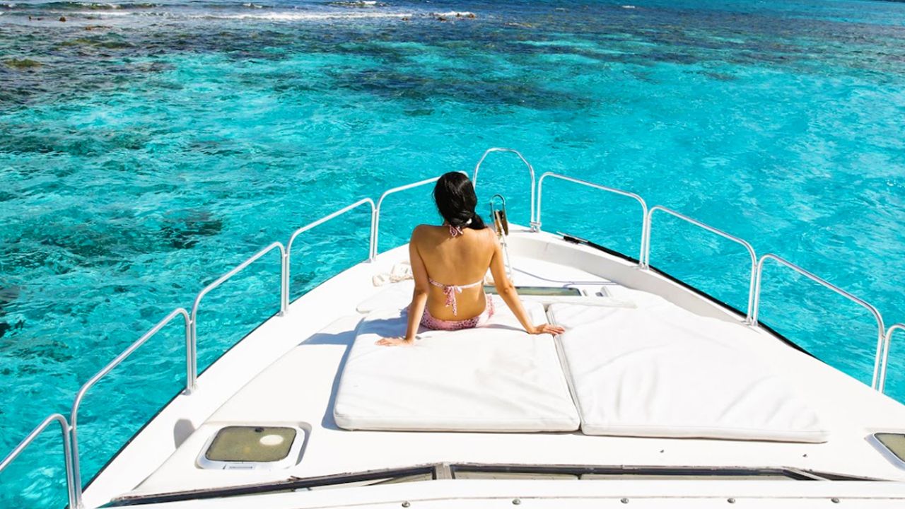 Guest sunbathing on the bow of a yacht over turquoise water