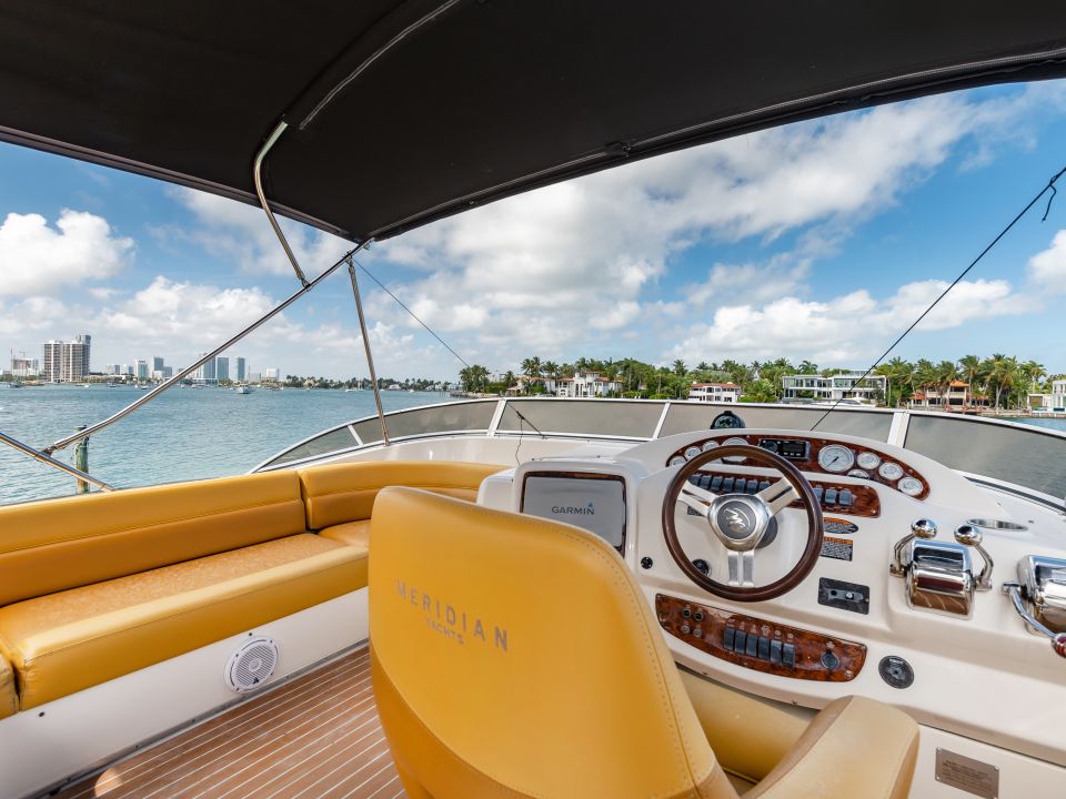 Flybridge helm with cream leather seating and instruments under a bimini top