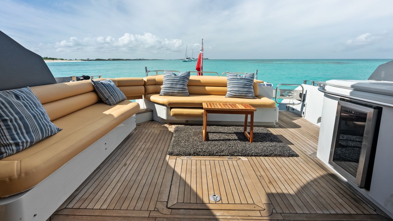 Teak aft deck of a motor yacht with cushioned lounge seating, a coffee table and open sea views