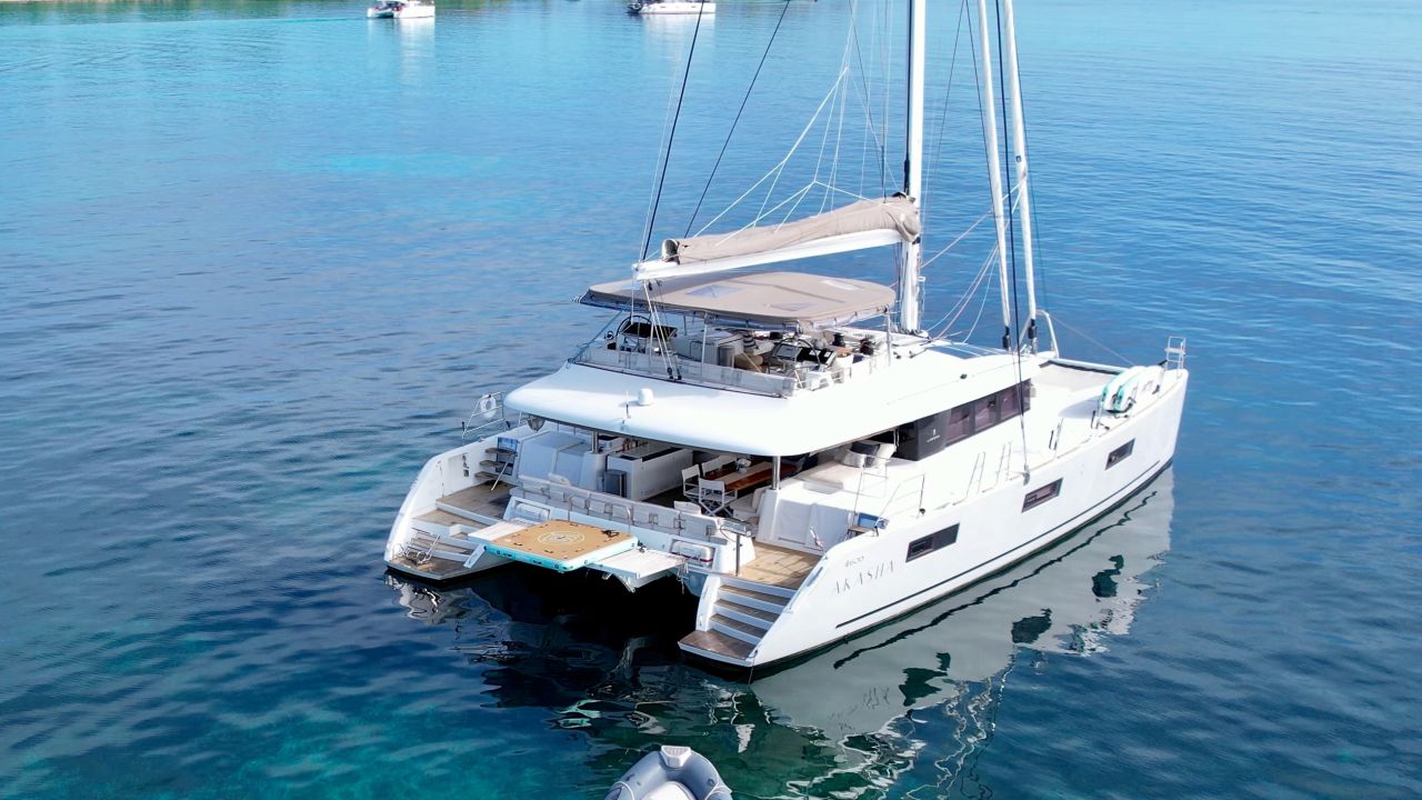 Sailing catamaran anchored in clear blue water with its tender alongside