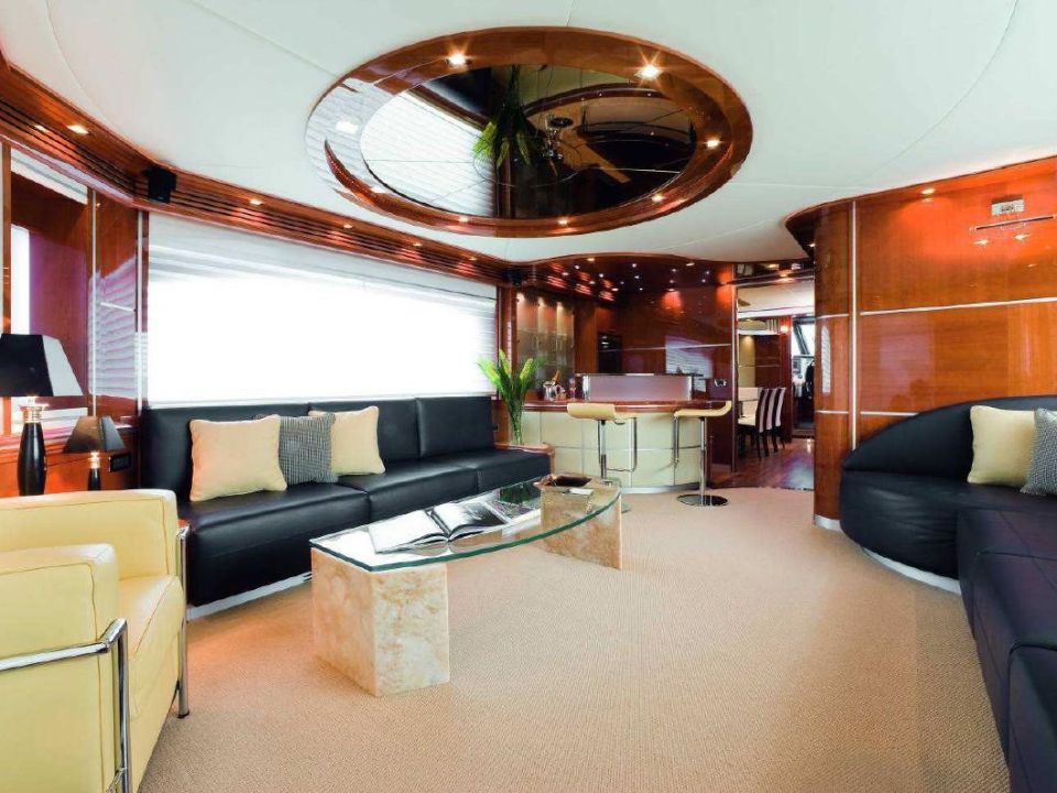 Yacht salon with dark leather sofas, polished wood and a mirrored ceiling