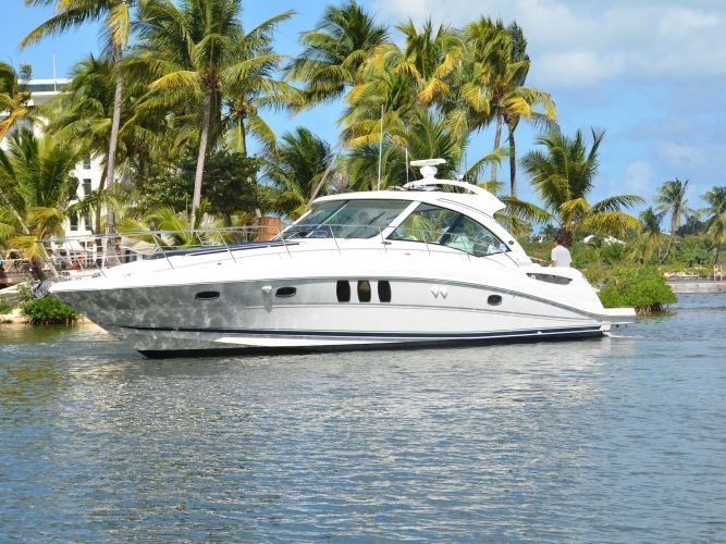 Motor yacht anchored in calm water off a beach lined with palm trees