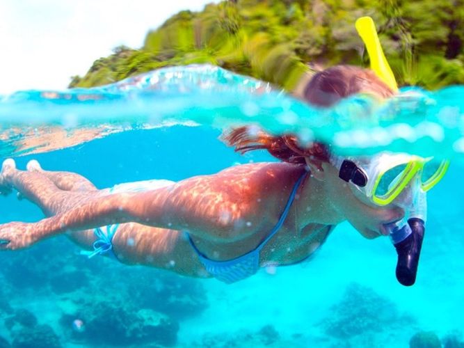Snorkeler in a mask and snorkel at the surface of bright turquoise water