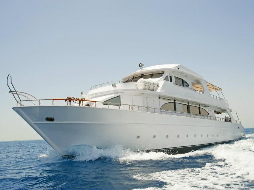 Large white superyacht cruising with spray at the bow