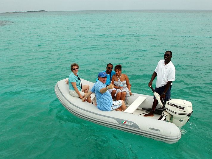 Guests riding in an inflatable tender across clear green water