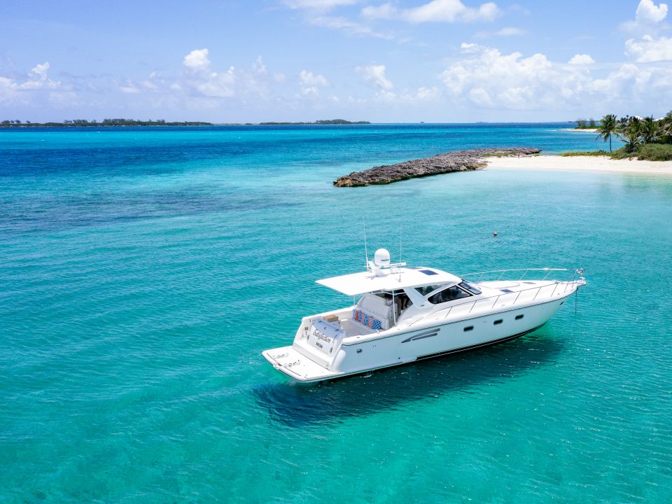 White motor yacht anchored in turquoise water near a beach