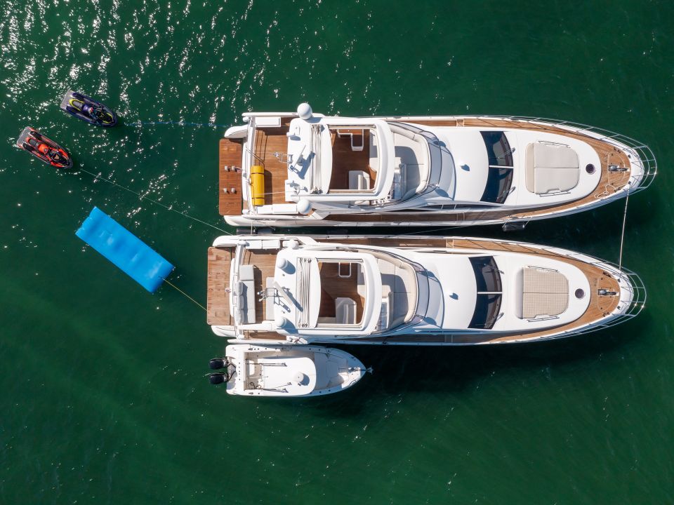Aerial view of two motor yachts at anchor side by side in deep green water
